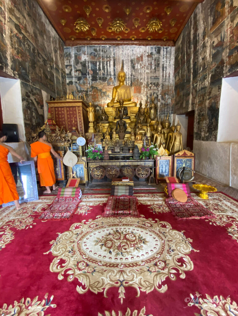 Vat Aham luang prabang temple has lots of darks reds and golden buddhas 