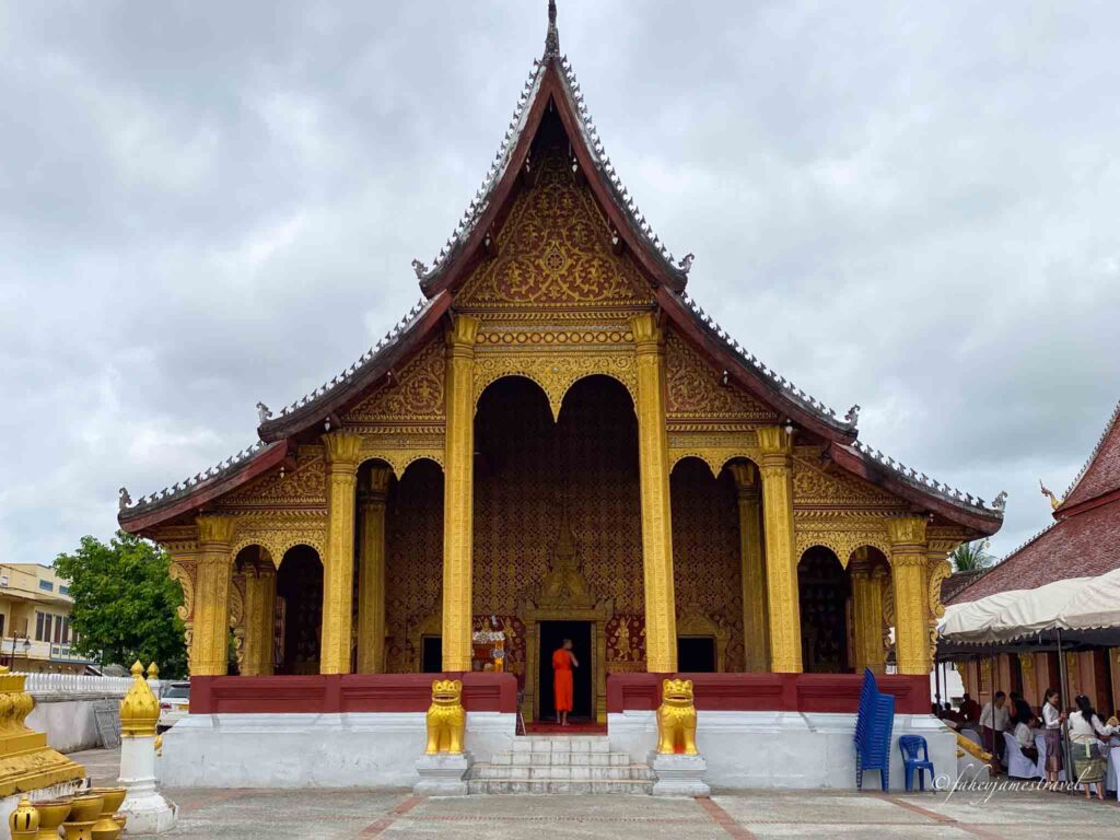 Vat Sensoukharam is pictured with gold and red colour and a monk at the door