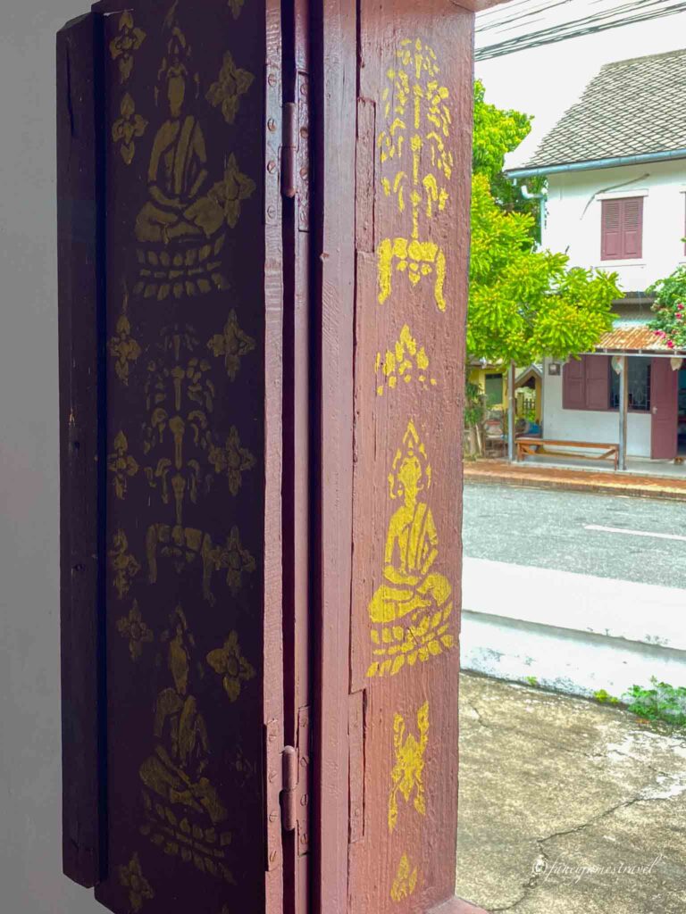 Vat Syrimoungkoun Xaiyaram is pictured with golden buddhas paintings on the window