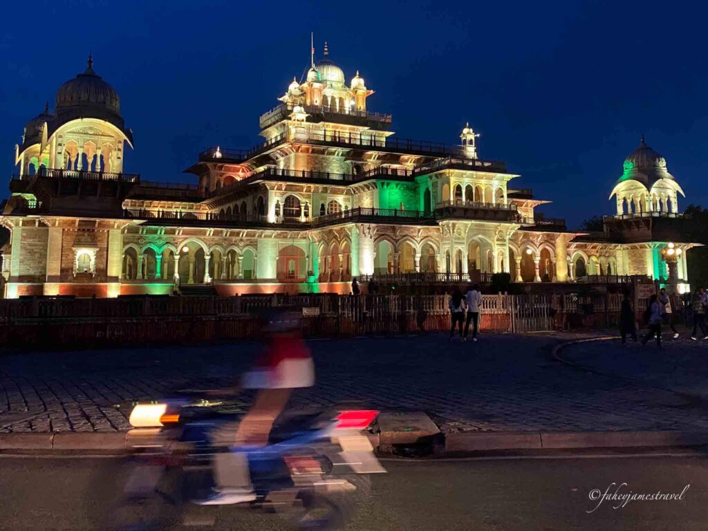 albert hall museum at night with green lights as a motorbike passes by