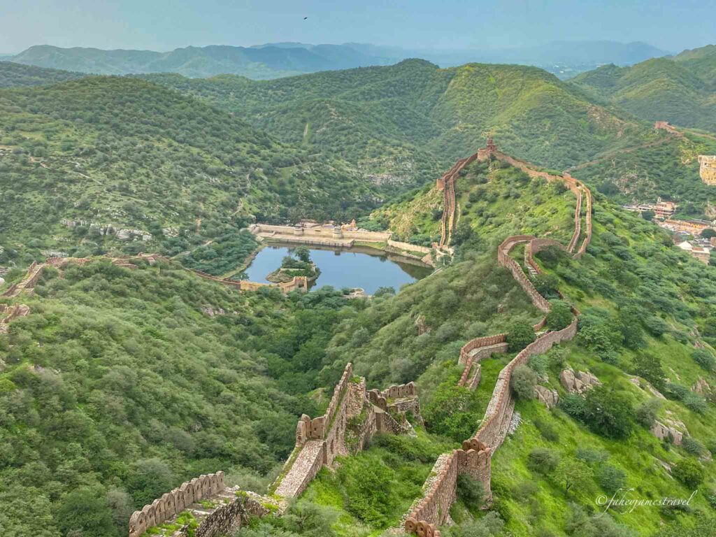 the walls of Jaigarh Fort are pictured throuhg the hills with lots of green and needs to be on your jaipur 2 day itinerary