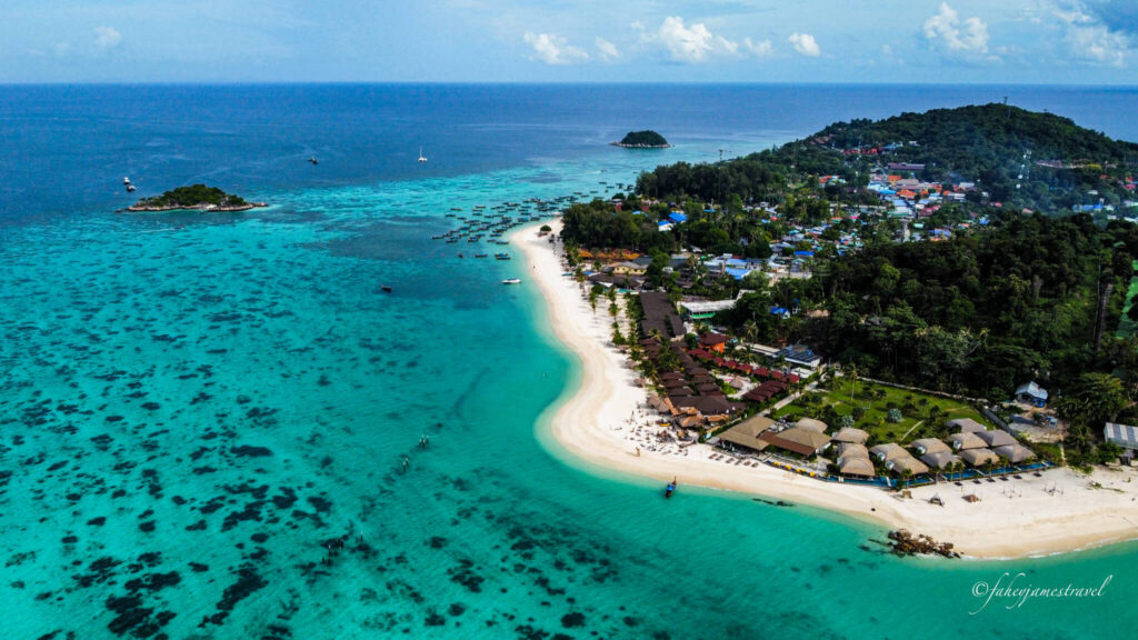 north point beach koh lipe. the sand is white and soft with clear blue water and few clouds in the sky. its a drone shot