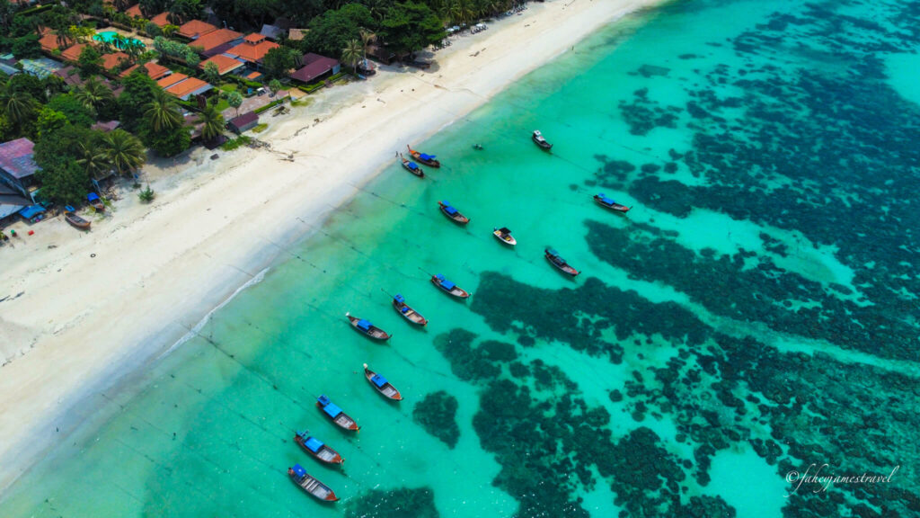 drone shot of pattaya beach koh lipe with some boats in the water and you can see the rocks in the sea