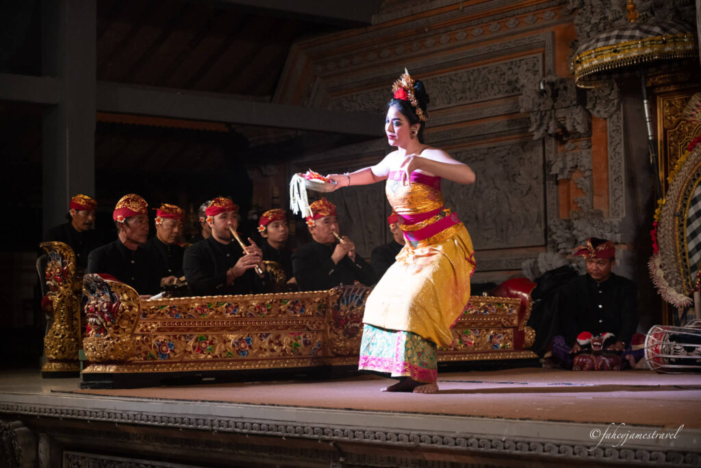 a lady dances on stage with her band in the background playing traditional balinese music 