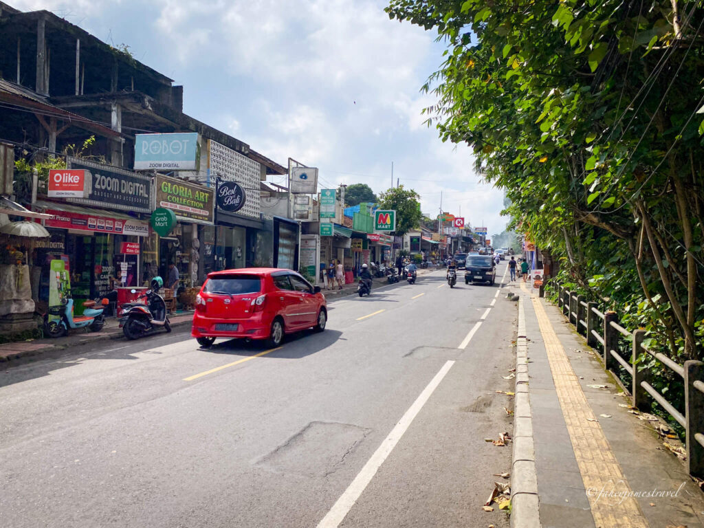 the street of ubud where one red car drives along the street 