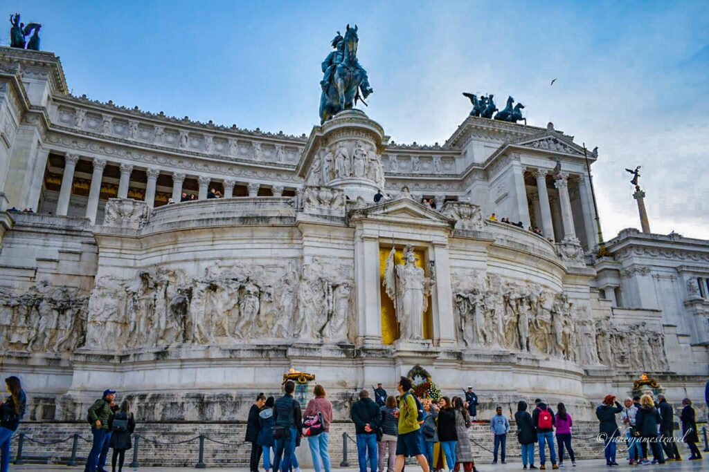 a clser up shot of the alter of the fatherland from a 90 degree angle. you can see a state at the top of the image and people stand around in the bottom 