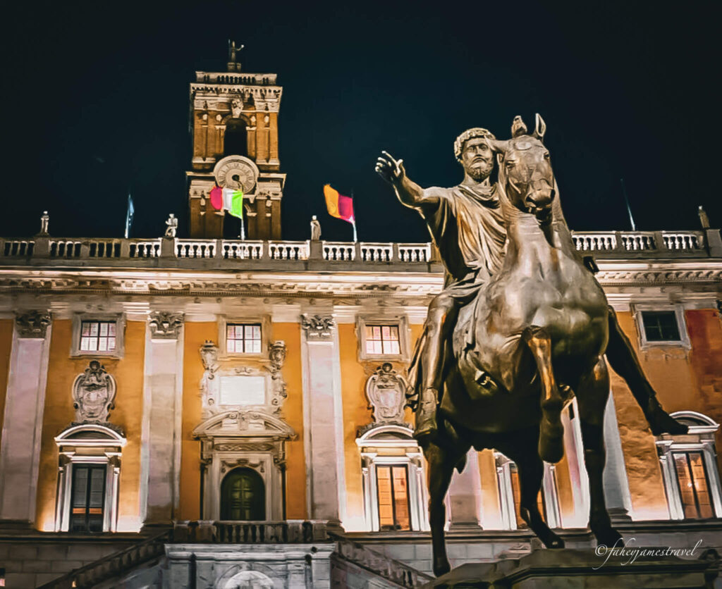 close up of the statue of marcus aurelius and the yellow building at the back with some flags 