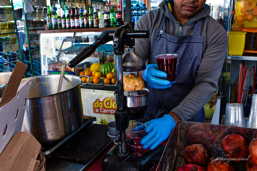a man hands me a pomegranate juice from the Campo de’ Fiori 