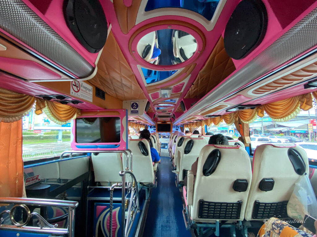 inside a minivan is shown from phuket to koh lanta. the colours are pinks and red and has leather beague seats 