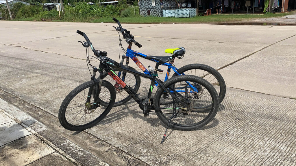 two bikes ist side by side outside koh lanta night market in the bright daylight