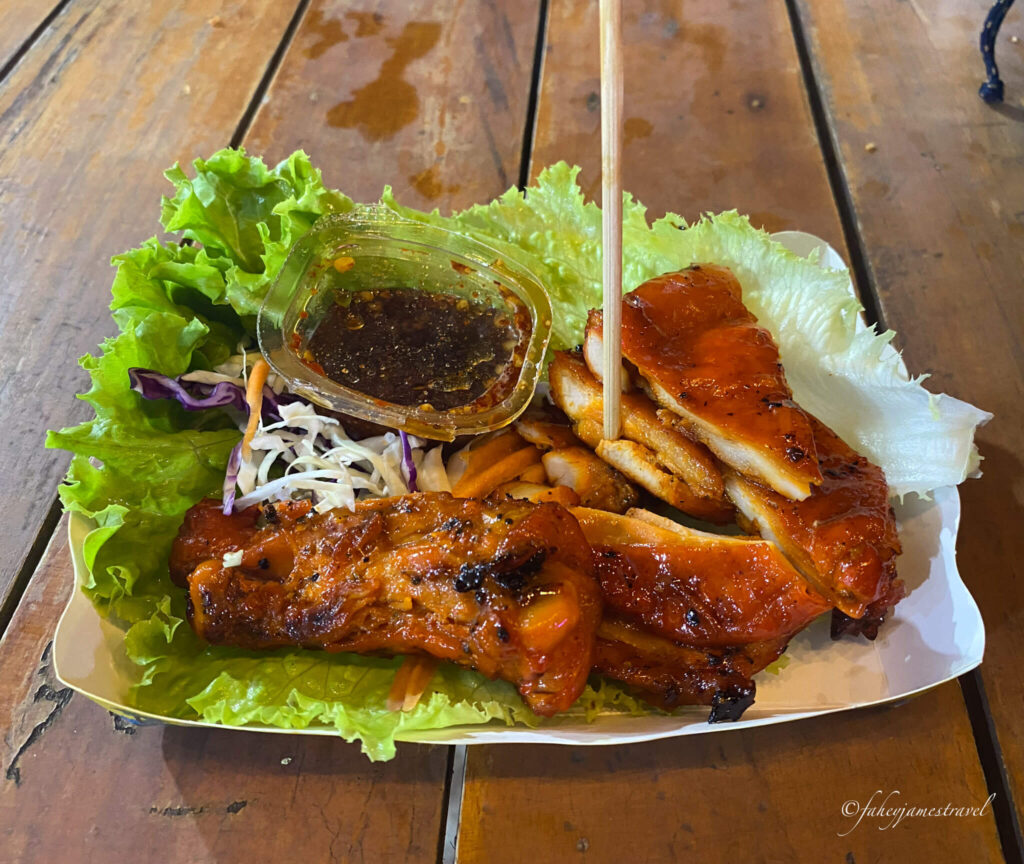 a close up of some pork, dip with a toothpick and some green salad leaves