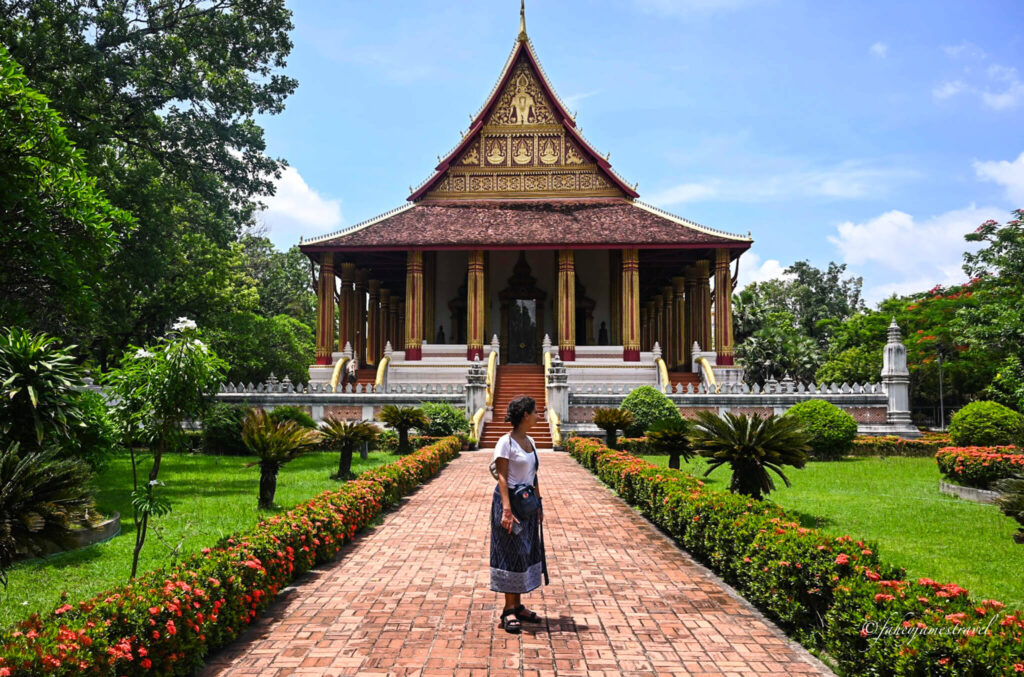 guada stands outside Wat Ho Phra Keo with the temple pictured in the background