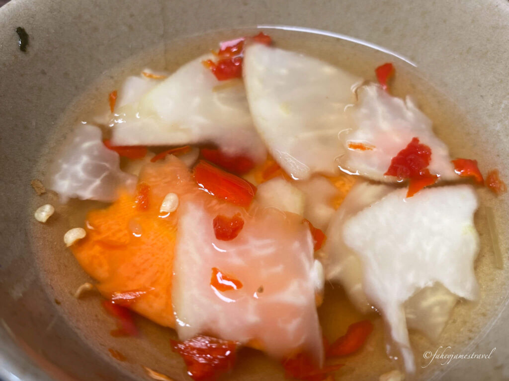 sweet and spicy dipping sauce for spring rolls is shown with some small pieces of cabbage