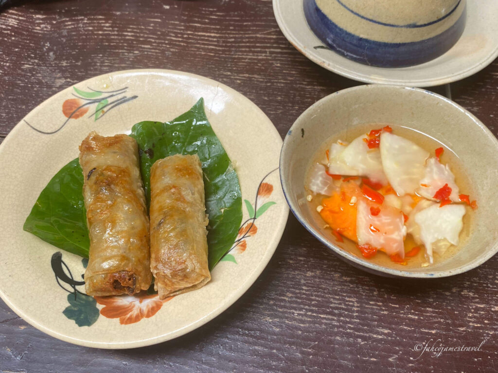 two spring rolls and dipping sauce is pictured on the table