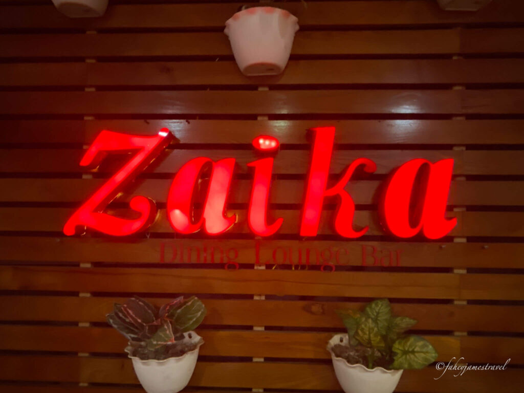Zaika Indian Restaurant has red letters on the inside of the restaurant 