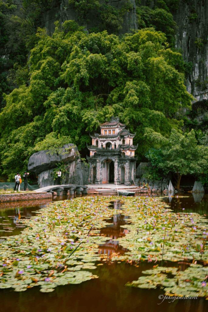 bich dong pagoda is pictured and the lake is in front with leaves on the water