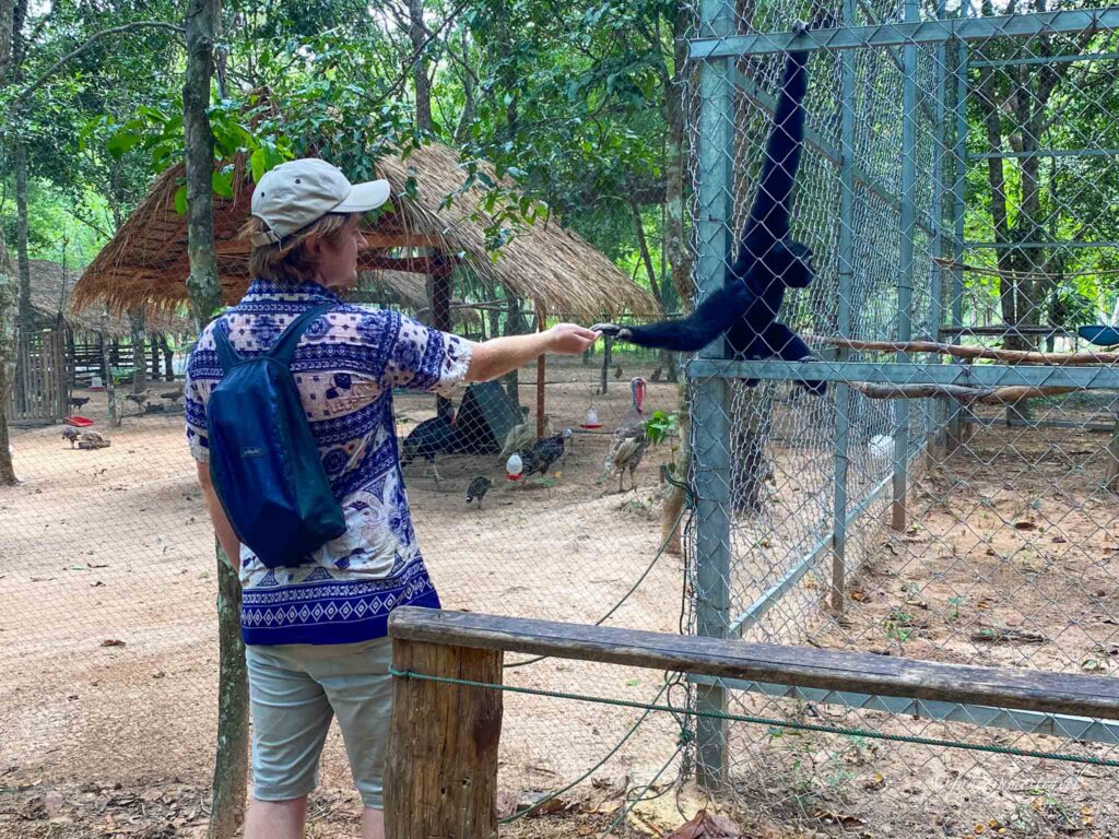 james holds a monkeys hand at angkor botanical garden